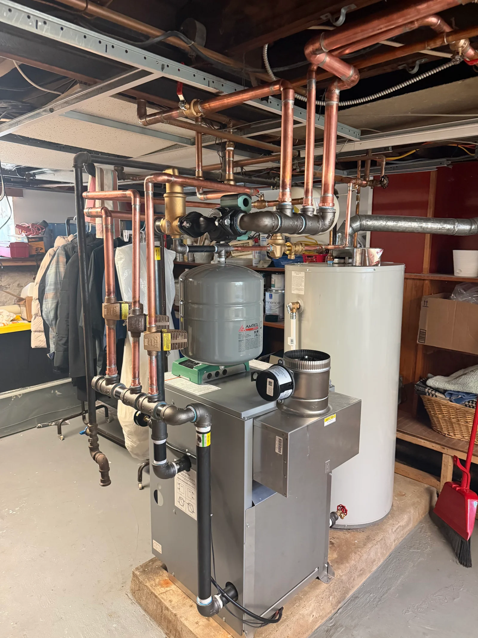 Stainless steel boiler with black iron and copper hydronic piping, Amtrol expansion tank, and adjacent water heater in a basement