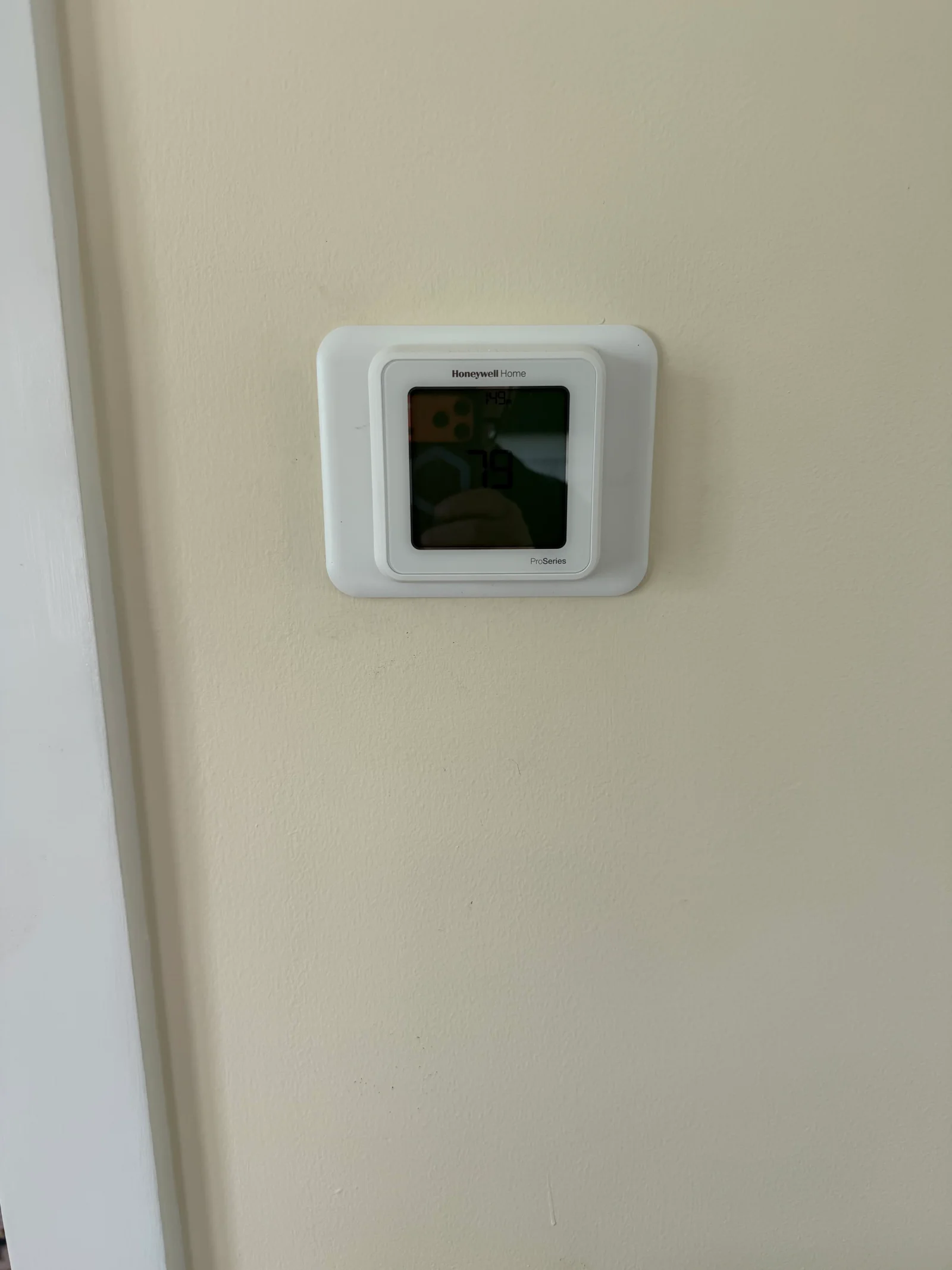 Honeywell Home ProSeries thermostat mounted on cream painted wall beside white door trim